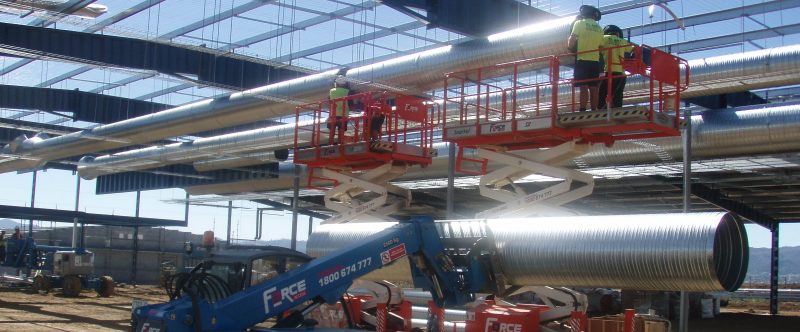 scissor lift with pipes on it at a construction site