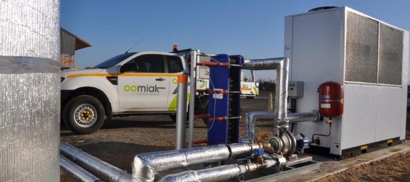 chilled water pump skid outside with a white car in the background with an oomiak logo on it