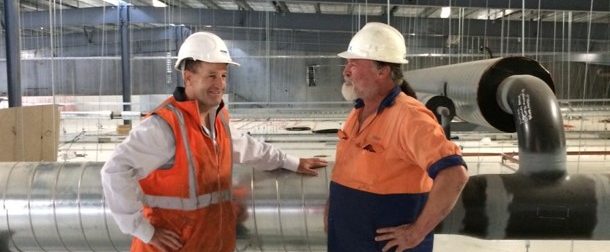 two men in hi vis wearing white hard hats in a construction site