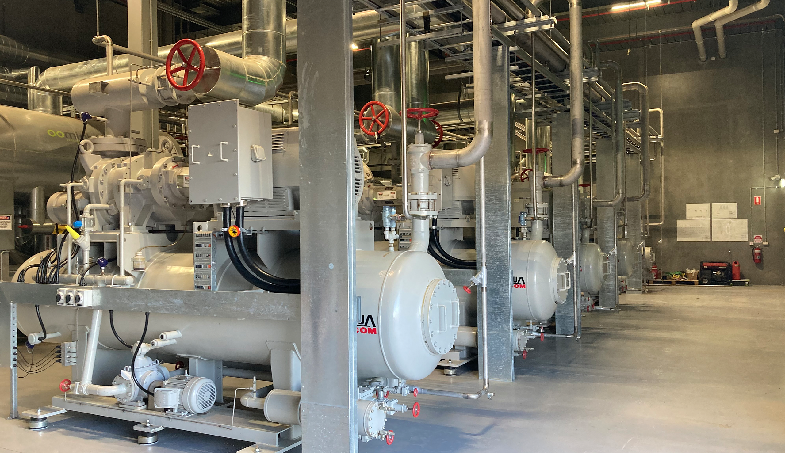 inside of an industrial refrigeration plantroom with five compressors in a row