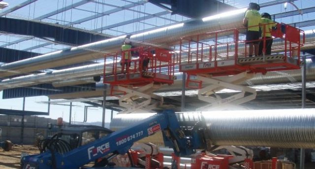 scissor lift with pipes on it at a construction site