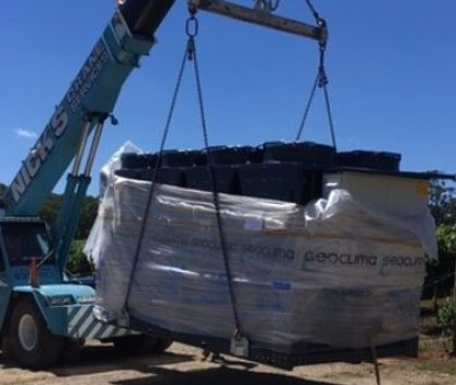 a crane carrying a refrigerated fluid chiller across a vineyard