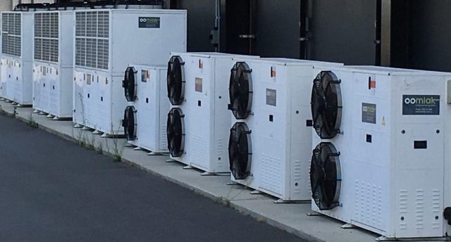 a line of eight industrial refrigeration equipment outdoors
