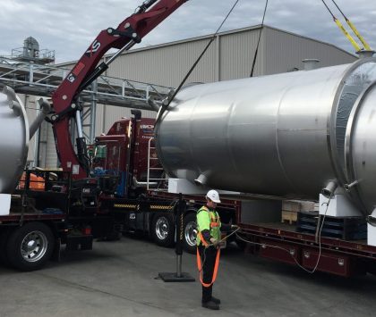 man standing in front of two trucks holding a cord