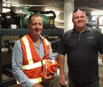 two men in a refrigeration plant room one is wearing hi vis the other is wearing a blue polo shirt