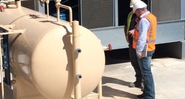 two men standing outside next to refrigeration equipment