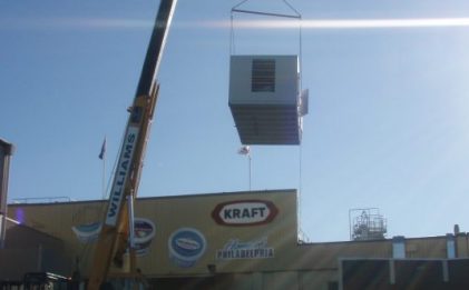 crane carrying an air handling unit above a building