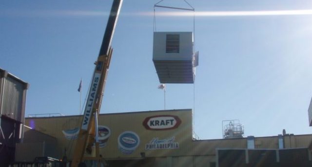 crane carrying an air handling unit above a building