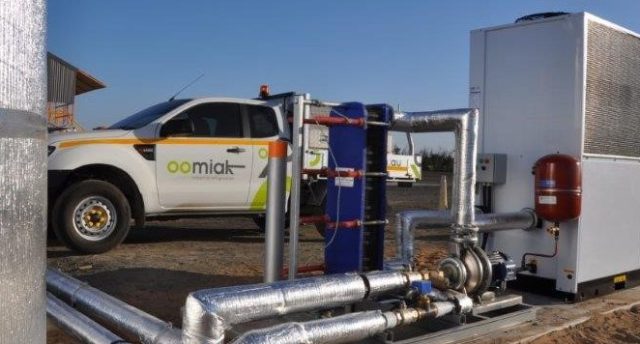 chilled water pump skid outside with a white car in the background with an oomiak logo on it