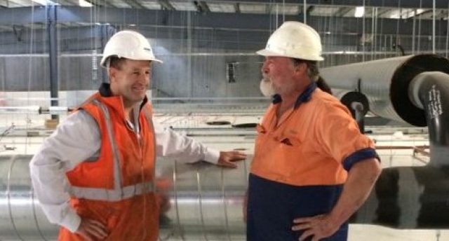 two men in hi vis wearing white hard hats in a construction site