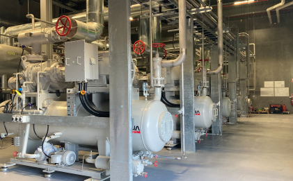 inside of an industrial refrigeration plantroom with five compressors in a row